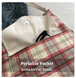 Close-up of portable front leather pocket on plaid tote bag holding black-frame glasses