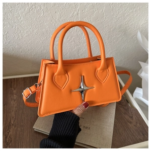 Détail du sac en cuir orange avec ornement étoile argentée et surpiqûres précises