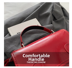 Detail of red textured leather mini backpack with black padded handle and contrast stitching