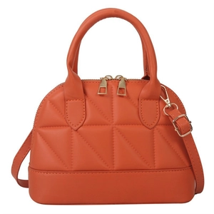 Orange quilted faux leather shell bag with gold hardware and removable shoulder strap