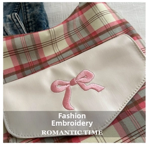 Detailed close-up of pink and green plaid fabric with romantic embroidery and a bow