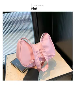 Détail du nœud rose sur un sac à bandoulière en cuir mat porté par un mannequin