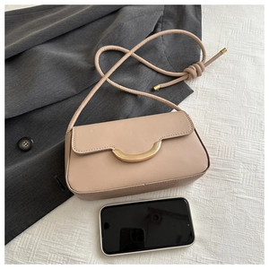 Détail du sac baguette crème minimaliste avec boucle dorée et bandoulière nouée