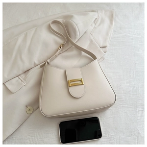 Detail of cream baguette bag with gold woven buckle on neutral texture background