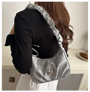 Silver pleated underarm bag with a butterfly charm and stylish ruffled shoulder strap detail