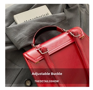 Detail view of deep red glossy leather backpack featuring adjustable straps and silver buckles