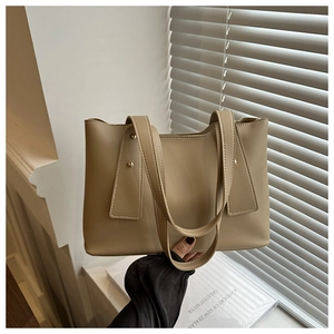 Detail of minimalist beige tote bag featuring gold hardware and elegant side stitching