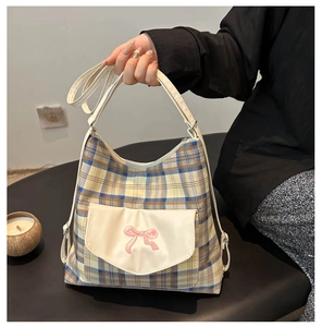 Detail of checkered tote bag featuring pink bow embroidery and white front pocket flap