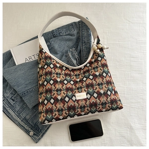 Detailed shot of multi-color geometric woven tote bag with FASHION label and beaded charm