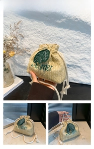 Detailed straw bucket bag with green Summer embroidery and leaf accents and white rope strap