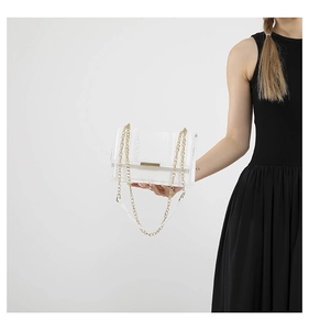 Close-up of white embossed square crossbody bag with gold chain strap and metal clasp