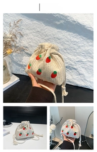 Detail view of woven straw bucket bag with red strawberry embroidery and drawstring closure