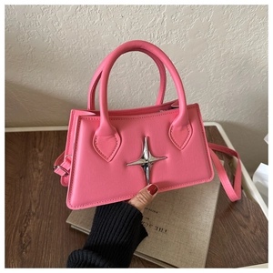 Détail du sac à bandoulière rose vif avec emblème d'étoile argentée et poignées solides