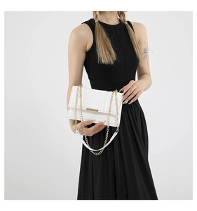 Close-up of white crossbody bag with gold metal chain strap and decorative front bar