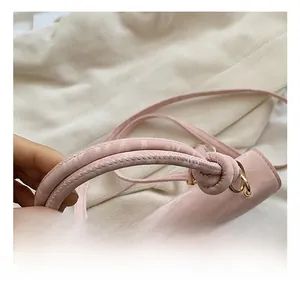 Detail of pink patent leather handbag featuring a knotted handle and gold hardware