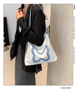 Modische Schmetterling-Schultertasche in Creme und Blau, getragen von einem Modell