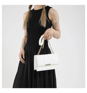 Detail of white leather shoulder bag with gold metal buckle and chain strap on model
