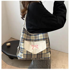 Detail of classic plaid tote bag featuring a white pocket with pink bow embroidery detail