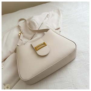 Detailed close-up of a cream-colored leather baguette shoulder bag with gold buckle