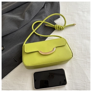 Sac bandoulière vert citron avec boucle dorée à côté d'un smartphone pour la taille réelle