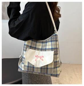 Detail of blue and yellow plaid tote bag with pink bow embroidery and white pocket