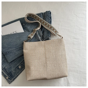 Detailed view of beige woven bucket bag with bohemian geometric pattern fabric strap