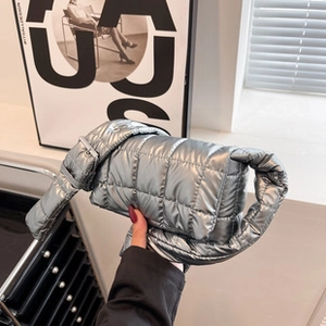 Detail of silver quilted puffer bag showing glossy metallic texture and wide strap