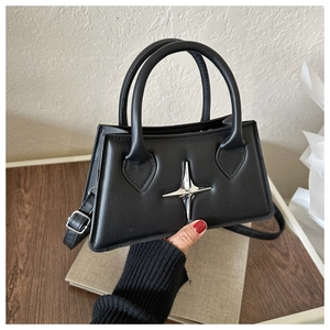 Détails d'un sac à main trapèze noir avec accessoire étoile argentée et bandoulière en cuir