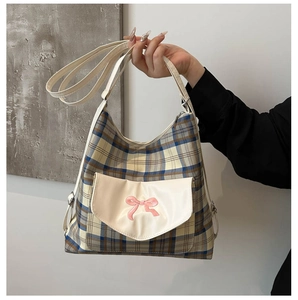 Close-up of canvas plaid tote bag with pink bow embroidery and front pocket detail