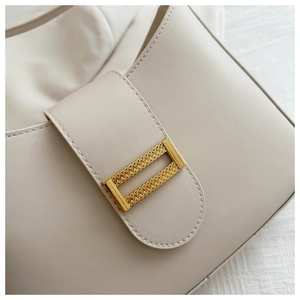 Macro shot of off-white leather handbag with a textured gold metallic buckle detail