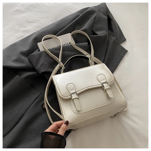 Detail of cream leather backpack featuring textured finish and twin buckle strap design