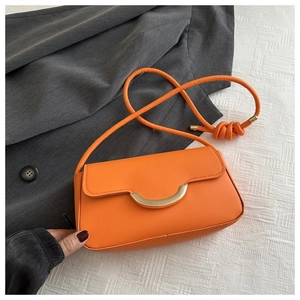 Détail du sac bandoulière orange avec boucle dorée en demi-lune et bandoulière nouée