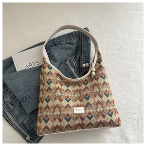 Detailed close-up of patterned nylon tote bag with white strap and fashion label
