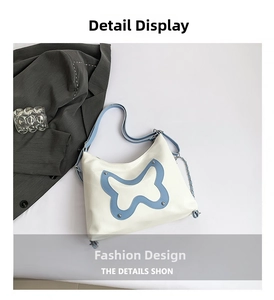 Nahaufnahme weiße Schultertasche mit blauem Schmetterlings-Patch und Nietenverzierung