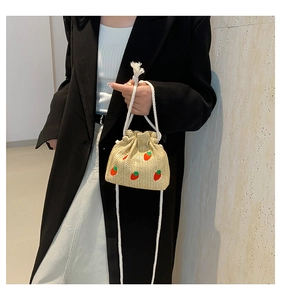 Detail of straw bucket bag with red strawberry embroidery and white drawstring