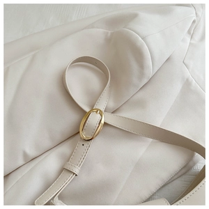Close-up of adjustable strap with gold oval buckle on cream faux leather shoulder bag