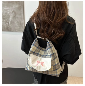 Detail of classic plaid tote bag with front white pocket and cute pink bow decoration