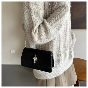 Détail du sac à bandoulière noir mat avec boucle étoile argentée et chaîne sur mannequin