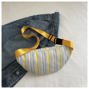 Gros plan du sac bandoulière plissé à rayures avec sangle jaune sur fond de denim bleu