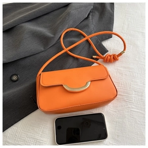 Détail du sac bandoulière en cuir orange avec boucle dorée en U et nœud sur la sangle