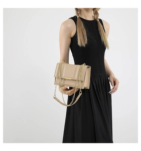 Detail of light apricot crossbody bag with gold metal bar and elegant chain strap