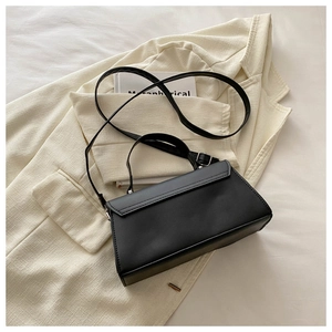 Flat lay of a structured black crossbody bag styled on a beige blazer background