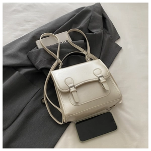 Detailed view of off-white PU leather backpack with buckle straps in a lifestyle setting
