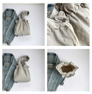 Detail view of light grey pleated tote bag with drawstring, ruffles and magnetic closure