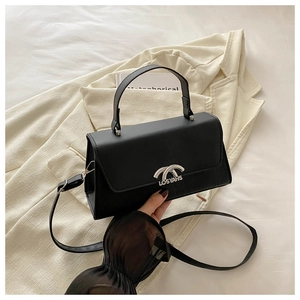 Detail of black leather handbag featuring a silver LOSYAHS buckle on a beige blazer