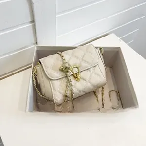 Detail view of beige quilted chain bag with gold hardware inside a white gift box