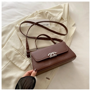 Detail of dark brown faux crocodile leather bag with silver metallic clasp and logo