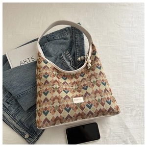 Detail of hobo bag featuring geometric woven pattern, pearl zipper, and fashion label