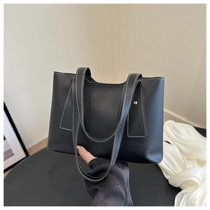 Detail of black leather square tote with white contrast stitching and metal rivet hardware