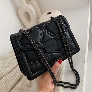 Detail of black quilted leather shoulder bag with metallic studs and chunky chain strap